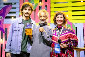Paulo Santos recebe o Troféu Homenagem ao Uakti das mãos de André Di Franco (Curadoria Temática) e Tamira Abreu (Realização e Direção Geral) Macacos Cine Fest / Foto: Luiza Wollny – Divulgação